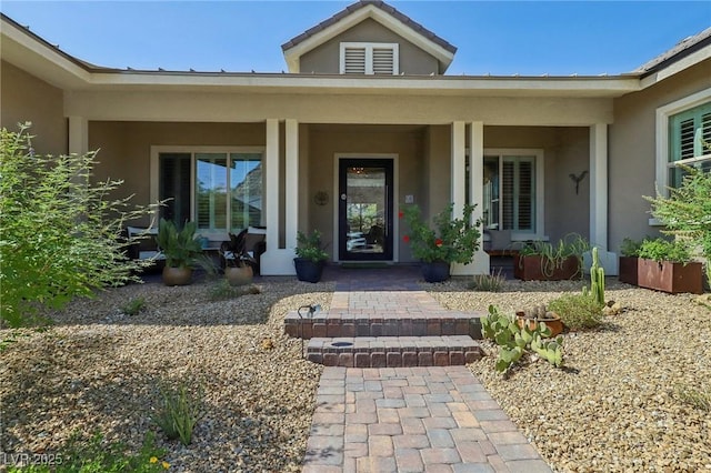 entrance to property with covered porch and stucco siding