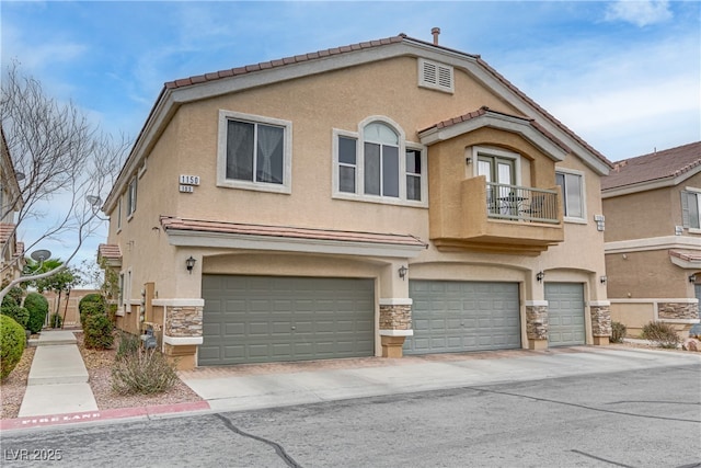 view of front of home featuring a garage, stone siding, a balcony, and stucco siding