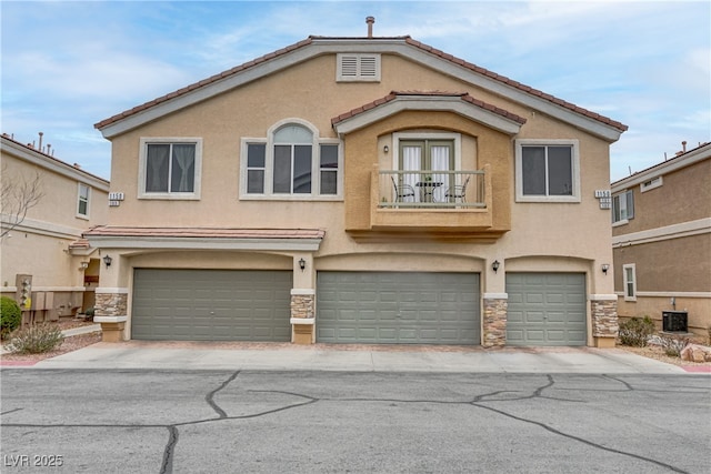 view of front facade with stucco siding, central AC unit, a balcony, a garage, and stone siding