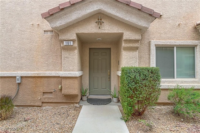 doorway to property featuring visible vents and stucco siding