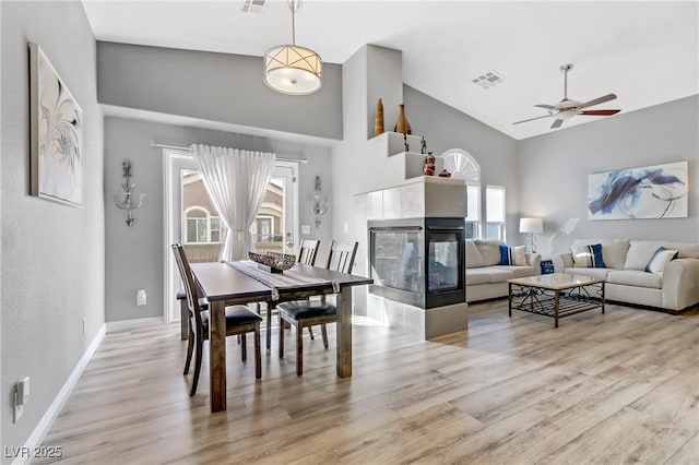 dining area featuring a tiled fireplace, visible vents, and wood finished floors