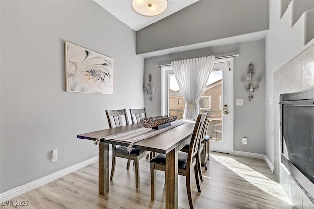 dining area with lofted ceiling, light wood-style flooring, and baseboards