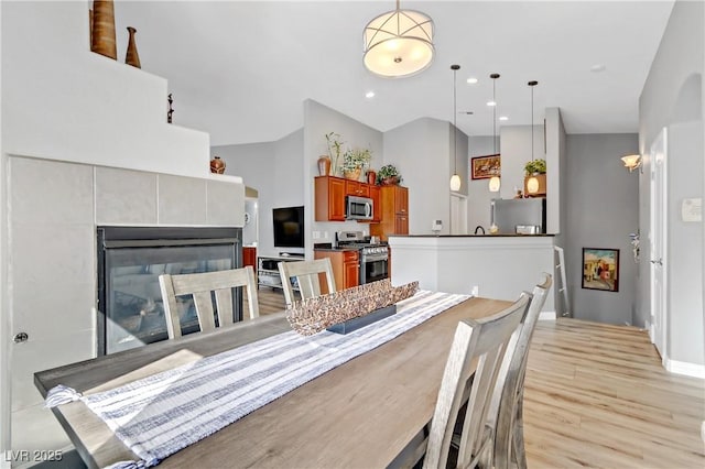 dining space featuring light wood finished floors, recessed lighting, and a tile fireplace