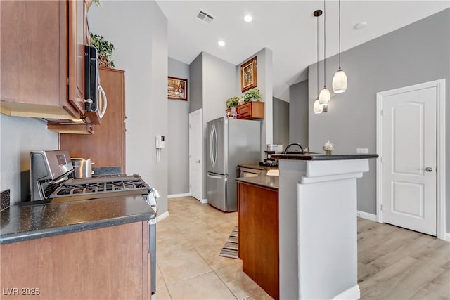 kitchen with pendant lighting, stainless steel appliances, dark countertops, visible vents, and brown cabinetry