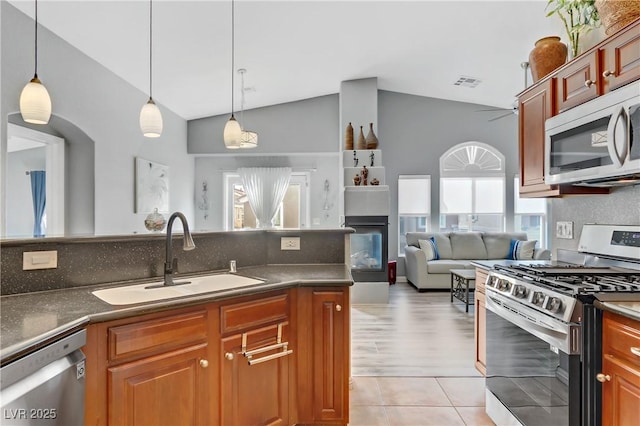 kitchen featuring a sink, visible vents, vaulted ceiling, appliances with stainless steel finishes, and a glass covered fireplace