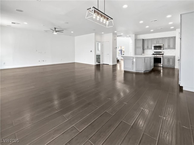 unfurnished living room featuring visible vents, a ceiling fan, dark wood finished floors, recessed lighting, and baseboards