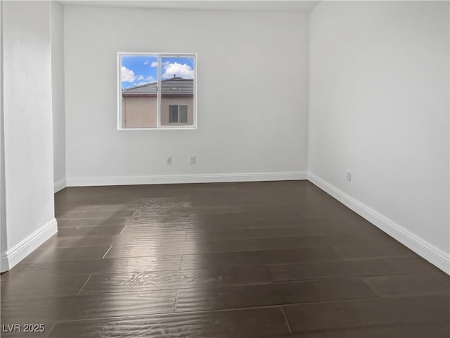 empty room featuring baseboards and dark wood-style floors