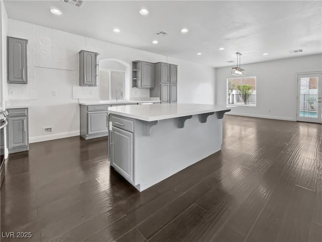 kitchen featuring open shelves, dark wood-type flooring, gray cabinetry, and light countertops