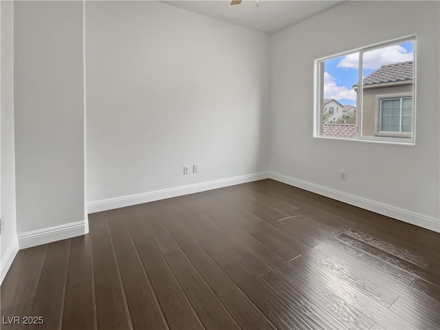 spare room featuring baseboards, dark wood finished floors, and a ceiling fan