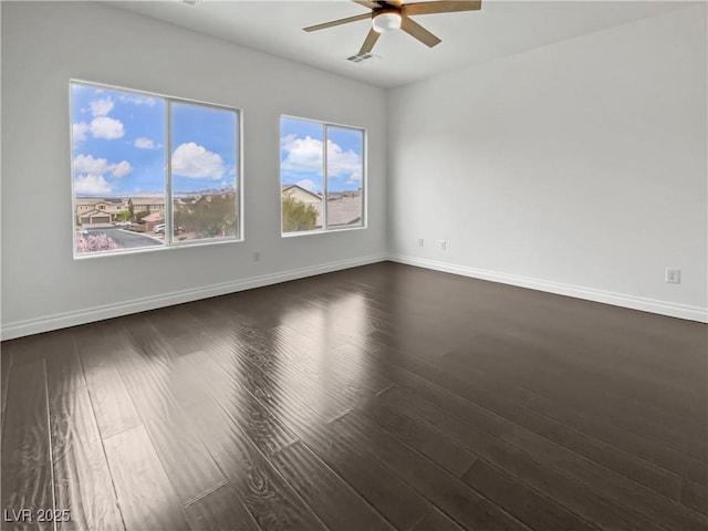 spare room featuring a ceiling fan, dark wood-style floors, visible vents, and baseboards