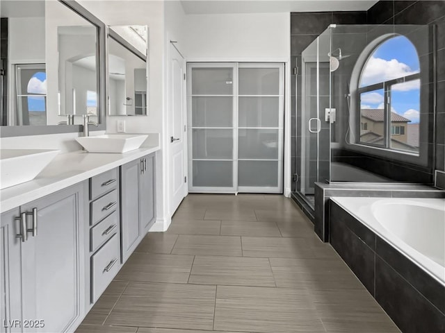 bathroom featuring double vanity, a stall shower, a garden tub, and a sink