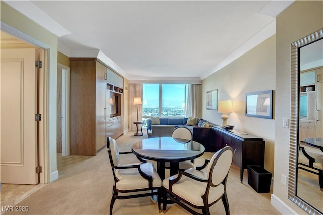 dining space featuring light colored carpet, crown molding, and baseboards