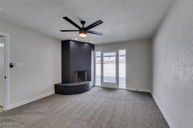 unfurnished living room featuring carpet, a fireplace, baseboards, and a textured wall