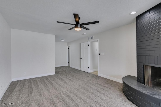 unfurnished living room with visible vents, a brick fireplace, baseboards, carpet flooring, and a textured ceiling