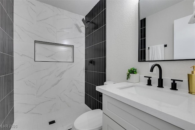 full bathroom featuring vanity, a shower stall, toilet, and a textured wall