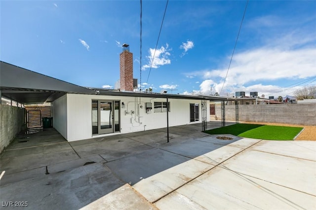 rear view of house featuring a patio area, a chimney, and fence