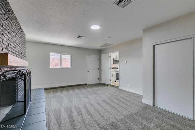 unfurnished living room with visible vents, a fireplace, a textured ceiling, and carpet