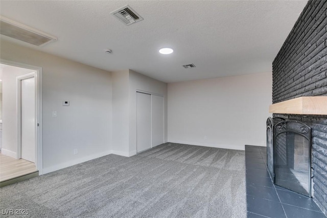 unfurnished living room with visible vents, carpet floors, a textured ceiling, and a brick fireplace