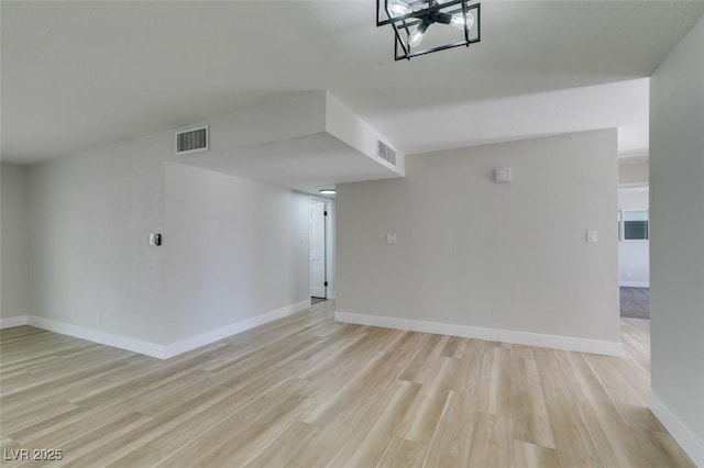 empty room featuring visible vents, baseboards, and light wood-style flooring