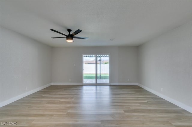 spare room featuring baseboards, ceiling fan, and light wood finished floors