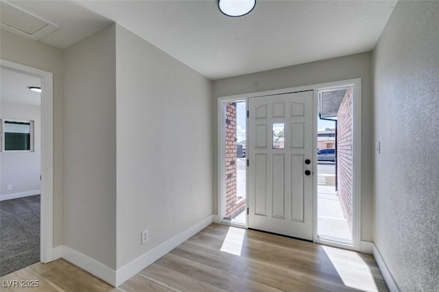 entrance foyer featuring baseboards, light wood-style flooring, and a textured wall