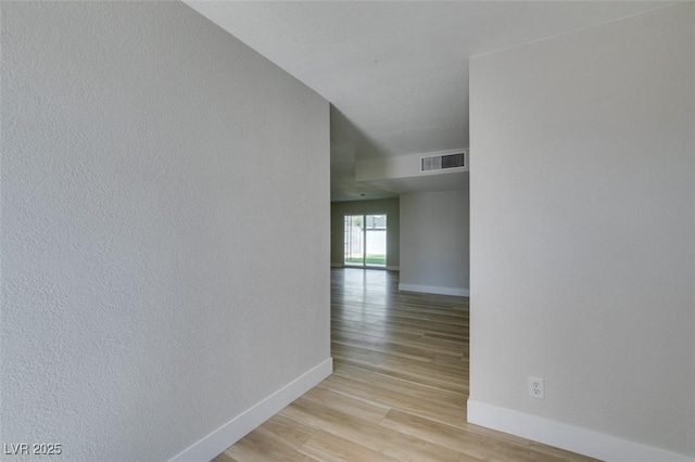 hall featuring visible vents, baseboards, and light wood-style floors