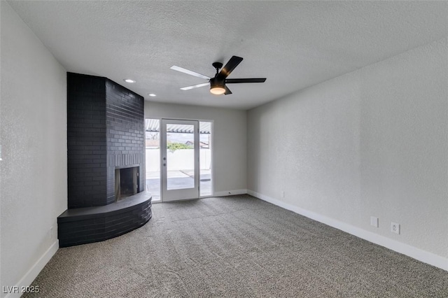 unfurnished living room featuring carpet flooring, a brick fireplace, a textured ceiling, and a textured wall