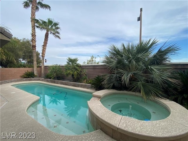 view of swimming pool featuring a pool with connected hot tub and a fenced backyard