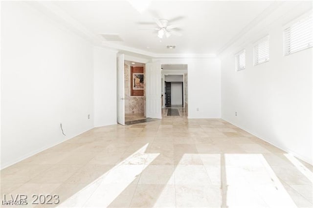 empty room featuring ceiling fan, visible vents, and crown molding