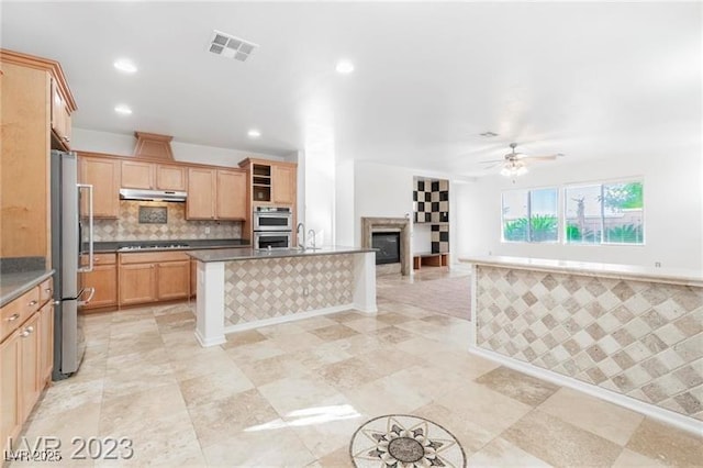 kitchen with visible vents, decorative backsplash, appliances with stainless steel finishes, open floor plan, and under cabinet range hood