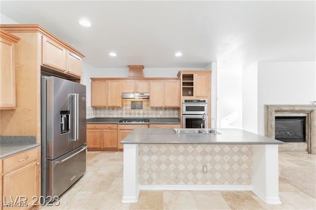 kitchen with stainless steel appliances, light brown cabinets, under cabinet range hood, and decorative backsplash