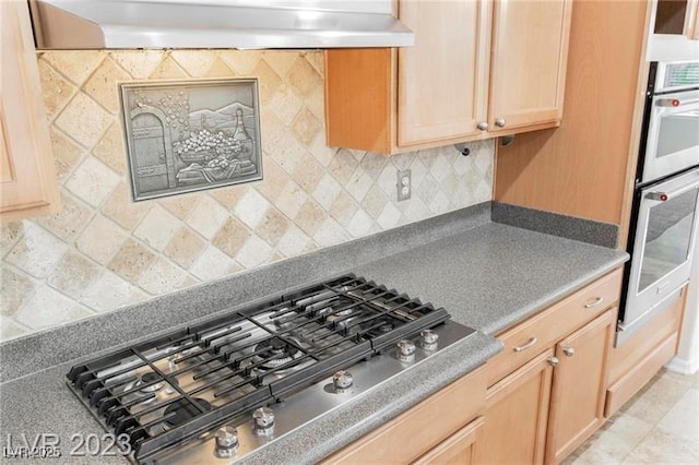 kitchen featuring stainless steel appliances, ventilation hood, light brown cabinets, and tasteful backsplash