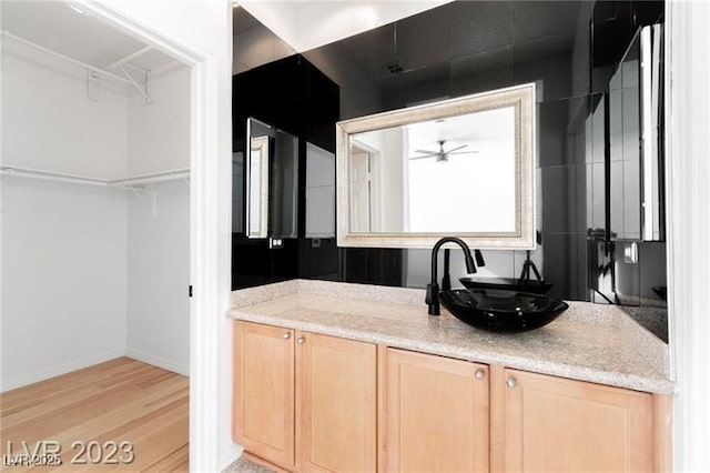 kitchen featuring baseboards, ceiling fan, light brown cabinetry, light wood-style floors, and a sink