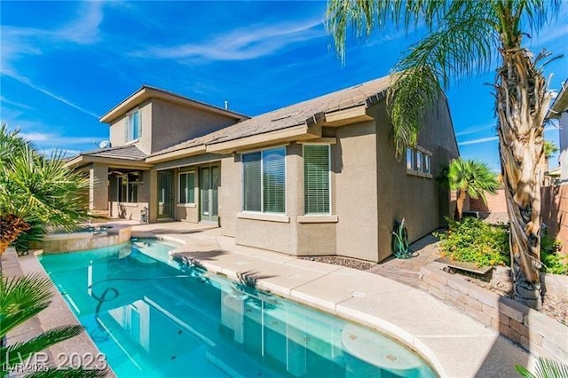 rear view of property with an outdoor pool, a patio area, fence, and stucco siding