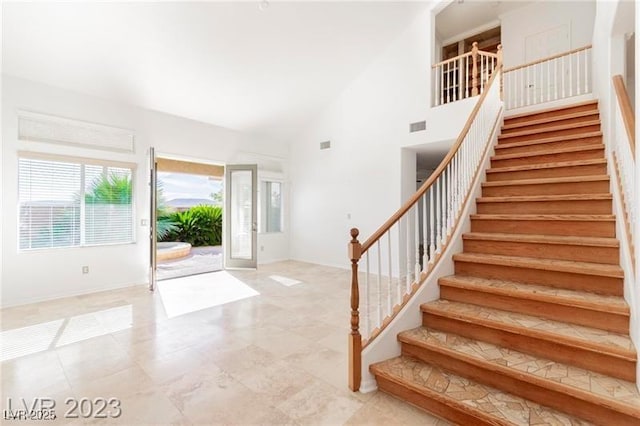 entrance foyer featuring visible vents, stairs, and high vaulted ceiling