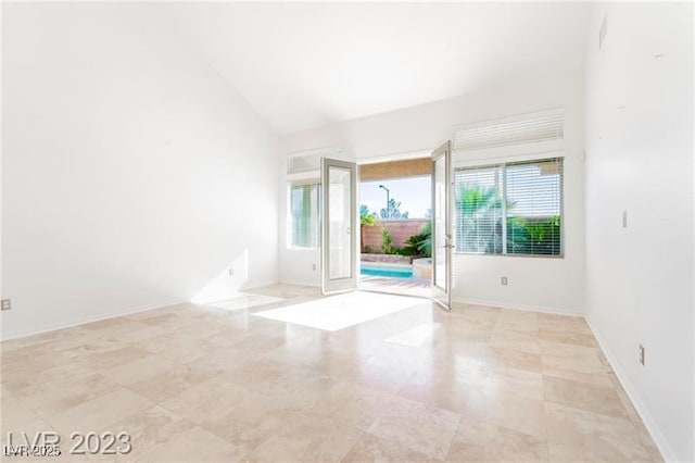 spare room with baseboards and high vaulted ceiling