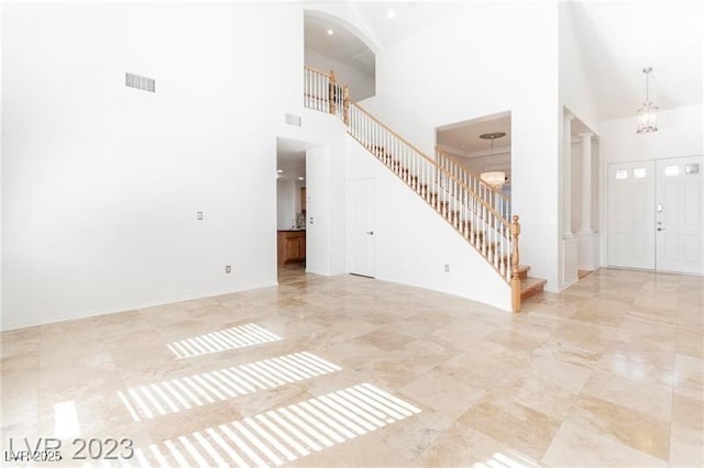 interior space featuring a towering ceiling, an inviting chandelier, visible vents, and stairway