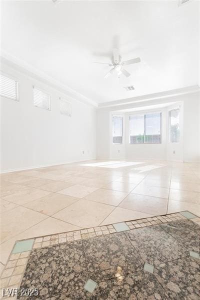 tiled spare room featuring ceiling fan, ornamental molding, and baseboards