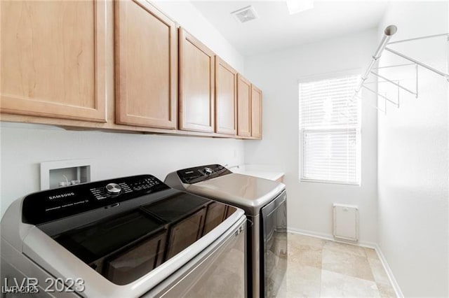 washroom featuring cabinet space, plenty of natural light, baseboards, and washer and clothes dryer