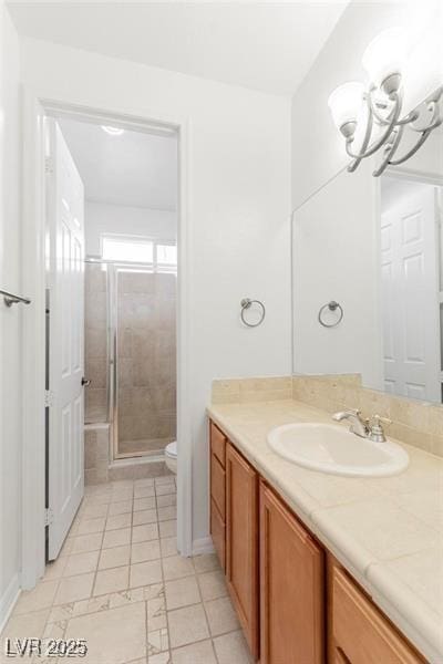 full bath with a stall shower, vanity, toilet, and an inviting chandelier