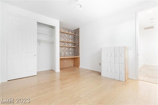 unfurnished bedroom with a closet, wood finished floors, and visible vents