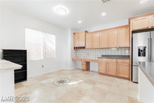 kitchen featuring high end refrigerator, visible vents, light brown cabinetry, built in desk, and backsplash