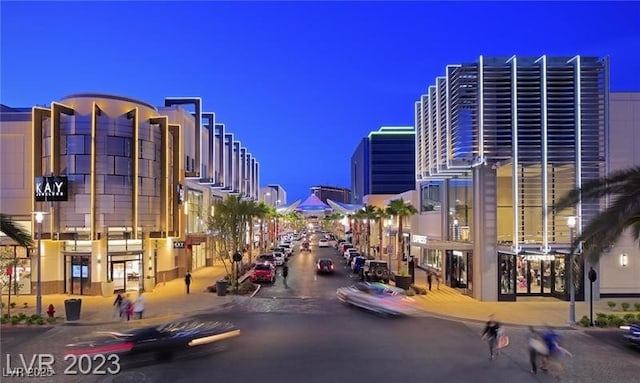 view of street featuring a view of city lights, curbs, sidewalks, and street lights