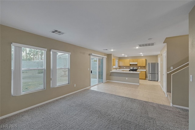 unfurnished living room featuring light tile patterned floors, visible vents, baseboards, and light colored carpet