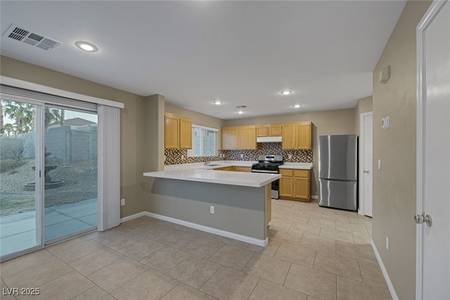 kitchen with visible vents, under cabinet range hood, appliances with stainless steel finishes, a peninsula, and light countertops