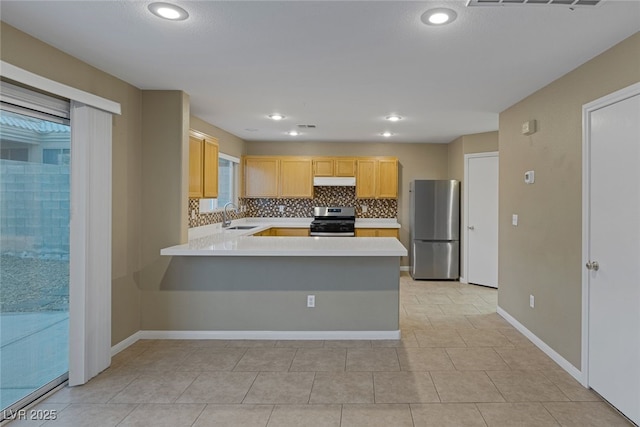 kitchen featuring tasteful backsplash, under cabinet range hood, light countertops, stainless steel appliances, and a sink