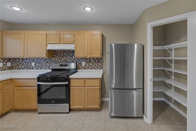 kitchen featuring light tile patterned floors, light countertops, under cabinet range hood, appliances with stainless steel finishes, and backsplash