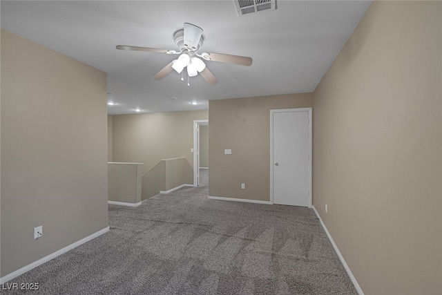 carpeted spare room with visible vents, baseboards, and a ceiling fan