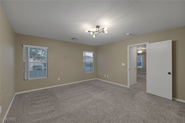 empty room featuring visible vents, baseboards, light colored carpet, and a textured ceiling