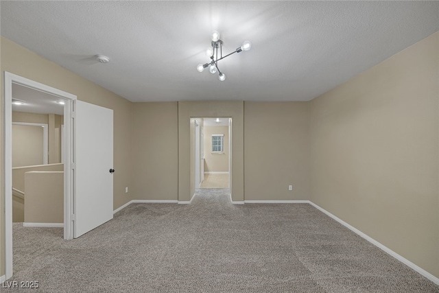 carpeted empty room with baseboards and a textured ceiling